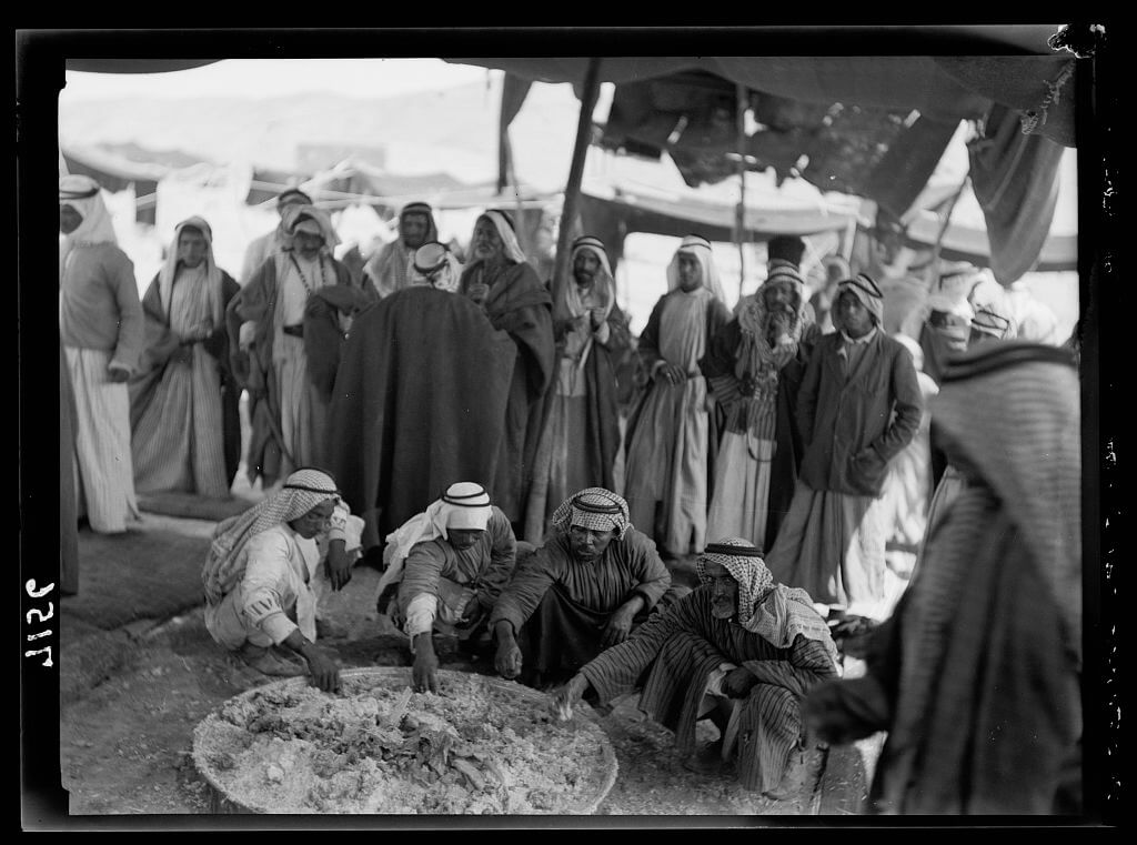 Bedouins eating around large tray in Shunet Nimrin