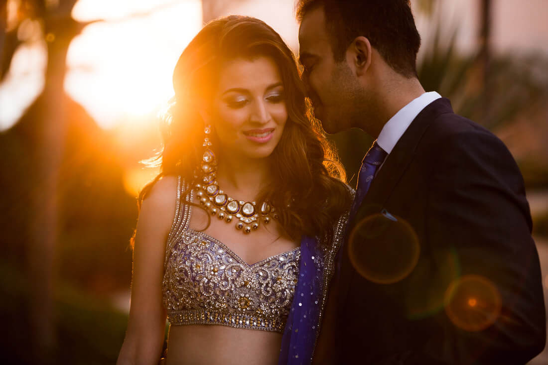 couple stands close together backlit by golden hour lighting