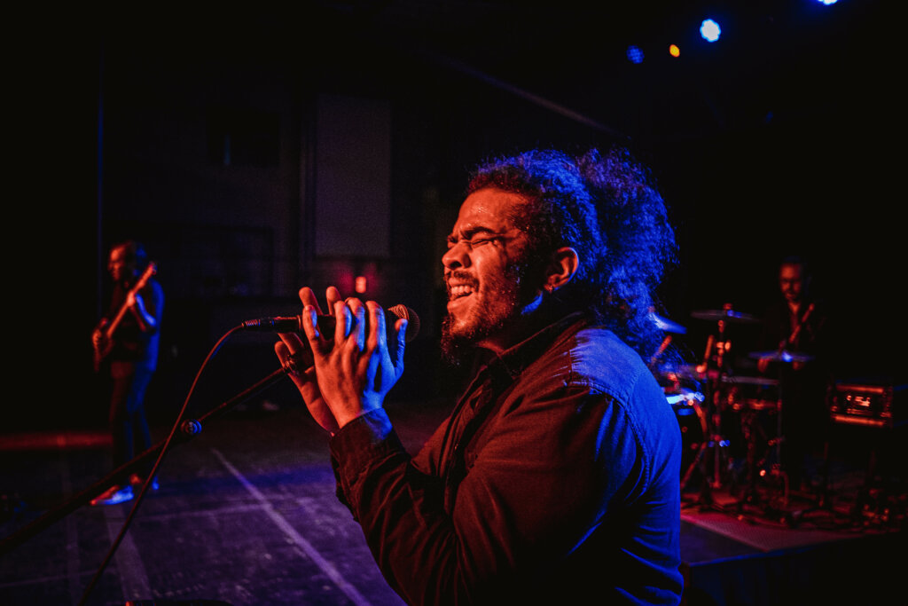 Singer singing with band on dark stage